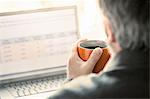 Over shoulder view of man browsing laptop at desk