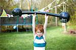 Young boy lifting pretend barbell, outdoors
