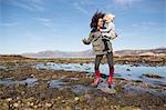 Mother holding son jumping in Loch Eishort, Isle of Skye, Hebrides, Scotland