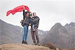 Family holding red flag in mountains, Fairy Pools, Isle of Skye, Hebrides, Scotland