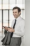 Portrait of mature businessman, using smartphone, smiling