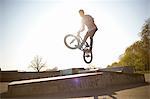 Young man, in mid air, doing stunt on bmx at skatepark