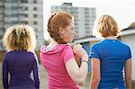 Rear view of three women standing together wearing sports clothing