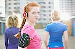 Portrait of woman wearing armband and headphones before exercise looking over shoulder at camera