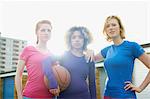 Portrait of three women exercising together holding a basketball