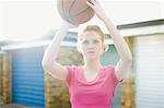 Portrait of woman holding basketball above head