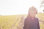 Girl strolling in field wearing headphones for metal detecting