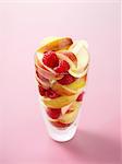 Glass full of raspberries and apple slices on pink background