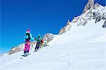 Rear view of mature male and female skiers moving up Mont Blanc massif, Graian Alps, France