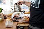 Hand of cafe waiter pouring boiling water into filter coffee pot