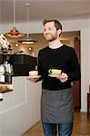 Cafe waiter serving cups of fresh coffee