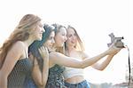 Four teenage girls taking instant camera selfie in park