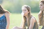 Teenage girl blowing bubble gum bubble in park