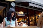 Young woman, sitting outside cafe, using smartphone, Shanghai, China