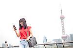 Young businesswoman, using smartphone, outdoors, Shanghai, China