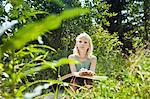 Young girl sitting in rural environment with sketchbook