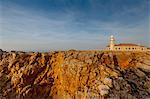 View of Punta Nati lighthouse on sunlit cliff, Menorca, Spain