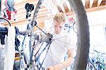 Mid adult man repairing bicycle, view through wheel