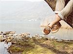 Mans feet dangling from tree on lakeside, Lake Mergozzo, Verbania, Piemonte, Italy