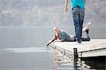 Young woman lying on pier at Lake Mergozzo, Verbania, Piemonte, Italy