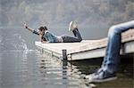 Young woman lying on pier splashing at Lake Mergozzo, Verbania, Piemonte, Italy