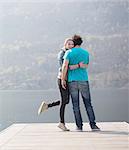 Young couple standing hugging on pier at Lake Mergozzo, Verbania, Piemonte, Italy