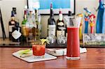 A classic Bloody Mary drink with celery on a table with a home bar in the background