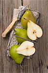 Green pears in a wire basket, whole and halved