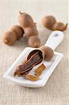 An open tamarind pod on a porcelain board