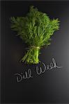 Fresh dill on a slate surface with a label