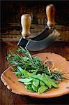 Mange tout and and bunch of herbs on a terracotta plate