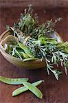 Mange tout and a bunch of herbs in a ceramic bowl