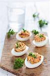 Devilled eggs with dried tomatoes and fresh parsley on a wooden board