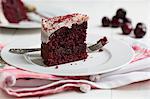 A slice of Red Velvet cake on a plate with a fork