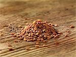 A pile of fenugreek seeds on a wooden surface