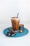 A glass of hazelnut iced coffee, brown sugar cubes and a wafer roll