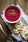 Beetroot soup served with slices of bread spread with cheese