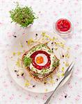A slice of wholemeal bread topped with beetroot aspic, egg, mayonnaise, cress and radish sprouts