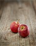 Two red apples on a wooden surface