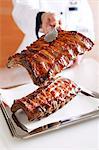 A chef holding grilled spare ribs with tongs