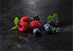 Fresh raspberries, blueberries and blackberries with leaves