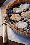 A mulberry pie with icing sugar topped with biscuits