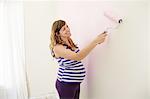 Pregnant woman painting nursery walls pink