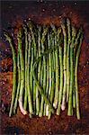 Fresh asparagus with olive oil and spices on a baking tray