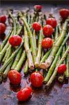 Asparagus and organic grape tomatoes with olive oil and spices on a baking tray