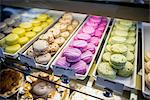 Macarons in trays in display cabinet, close-up
