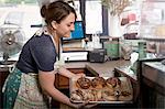 Bakery owner placing tray of doughnuts into display case