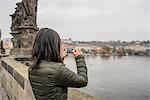 Rear view of woman using smartphone on Charles Bridge, Prague