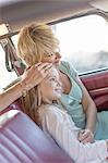 Grandmother and granddaughter sitting in back seat of car, smiling