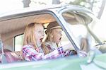 Two young girls driving car, looking scared